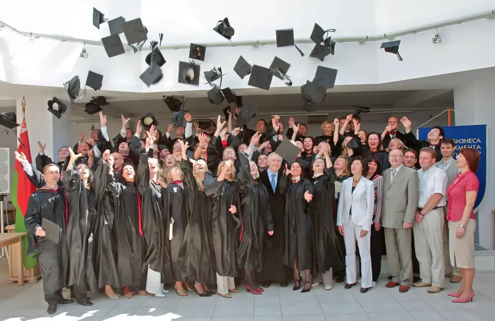 MBA graduation ceremony — group of graduates in black academic regalia smiling
